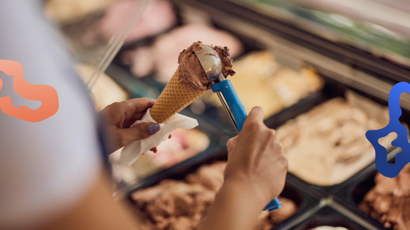 Person med behovsanställning eller timanställning jobbar i en glassbar och förbereder kulglass till en kund.