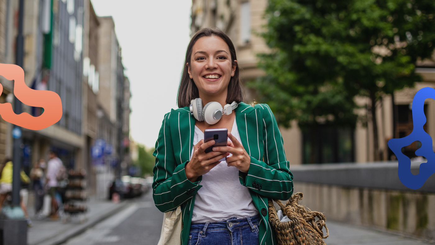 Glad person står med en smartphone i handen och söker jobb man kan få utan utbildning