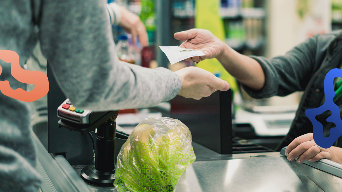 En butikssäljare jobbar i kassan i en butik och tar betalt av en kund.