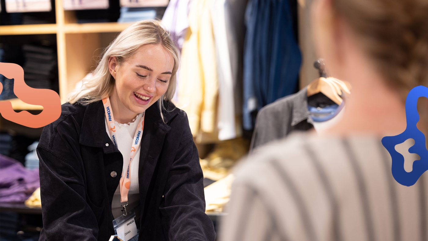 Butikssäljare som har jobb i en klädbutik hjälper en kund.