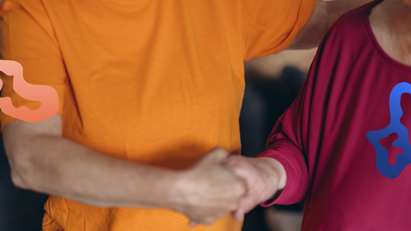 Person som jobbar på äldreboende håller en äldre människas hand.