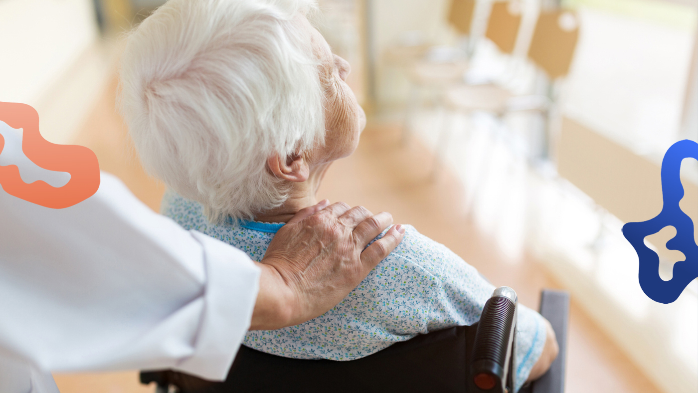 Person med offentligt jobb inom vården hjälper en äldre kvinna i rullstol.